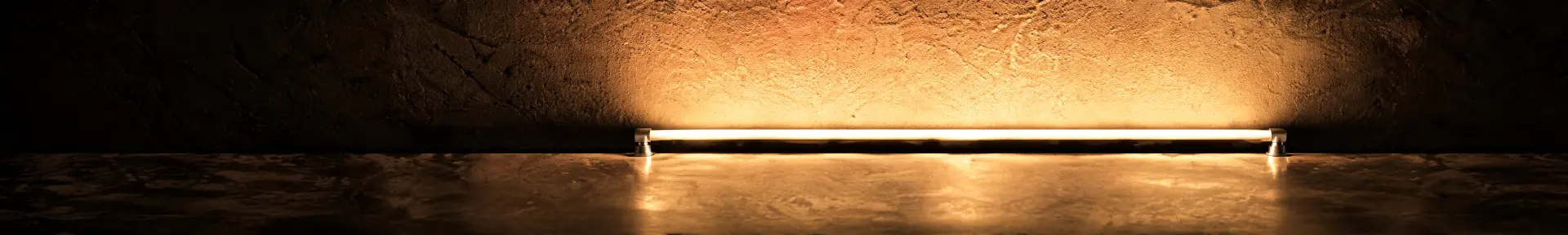 Waagrechter Lichtstab mit warmweißem Licht vor einer Wand